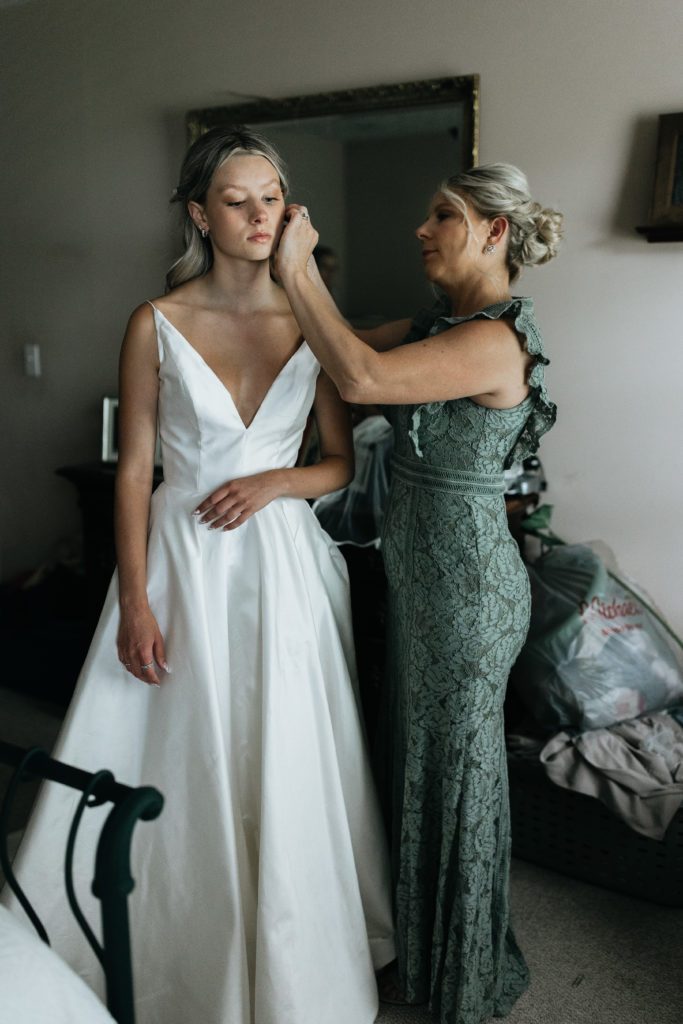 mom helping bride with earrings