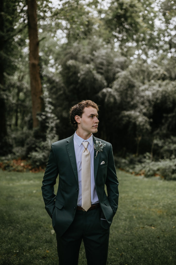 groom standing in forest