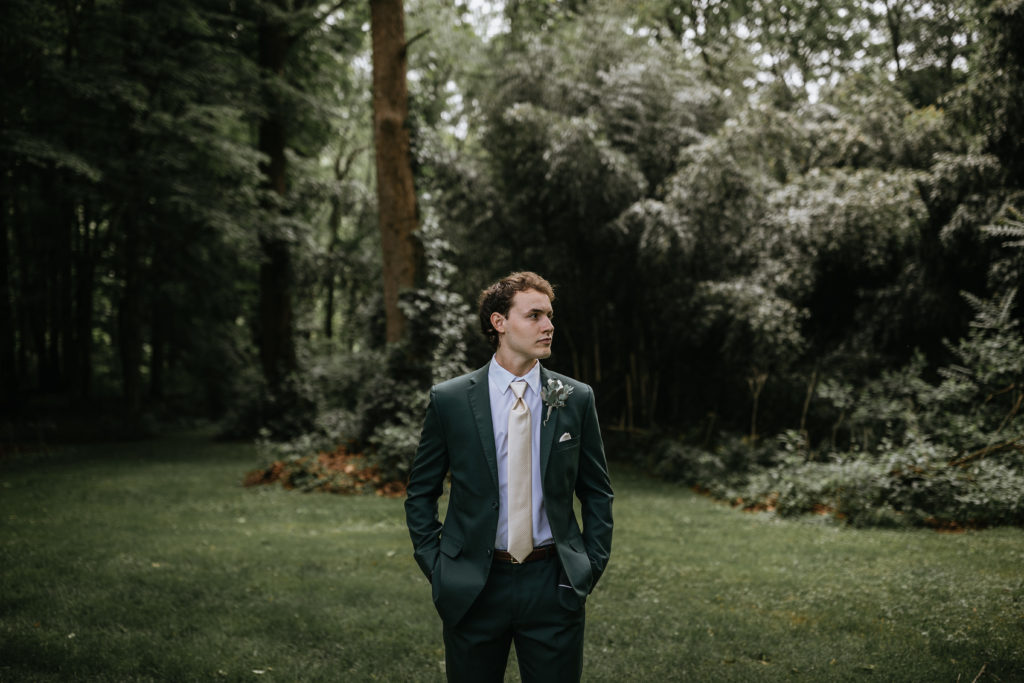 groom standing in forest