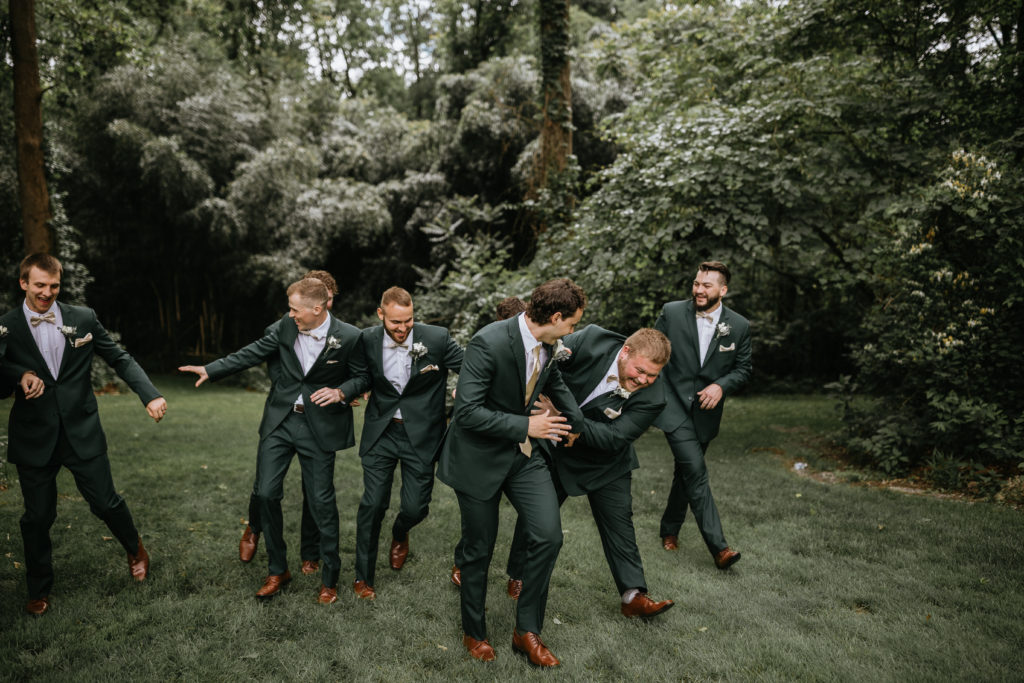 grooms and groomsmen standing in forest
