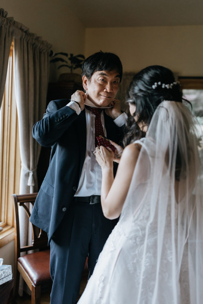 Bride helping dad with tie