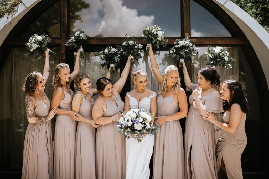 bride and bridesmaids holding flowers up