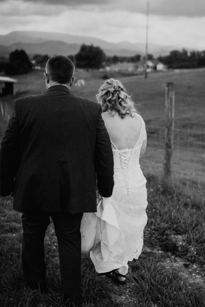 black and white photo of bride and groom walking away
