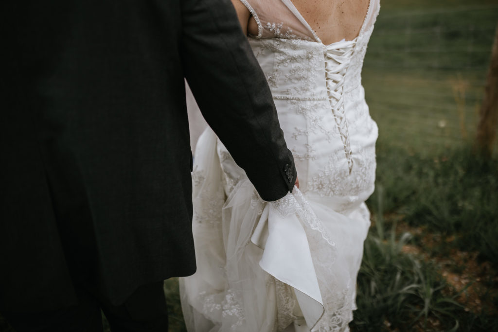 photo of groom holding brides dress while walking
