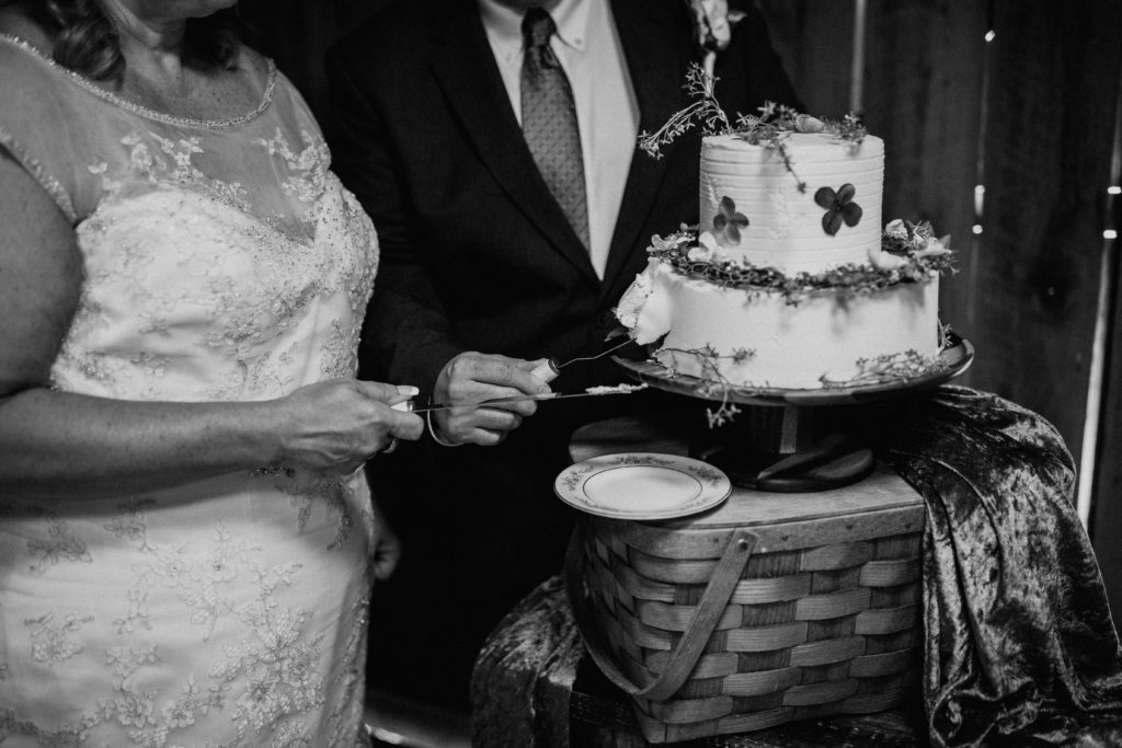 black and white photo of bride and groom cutting cake