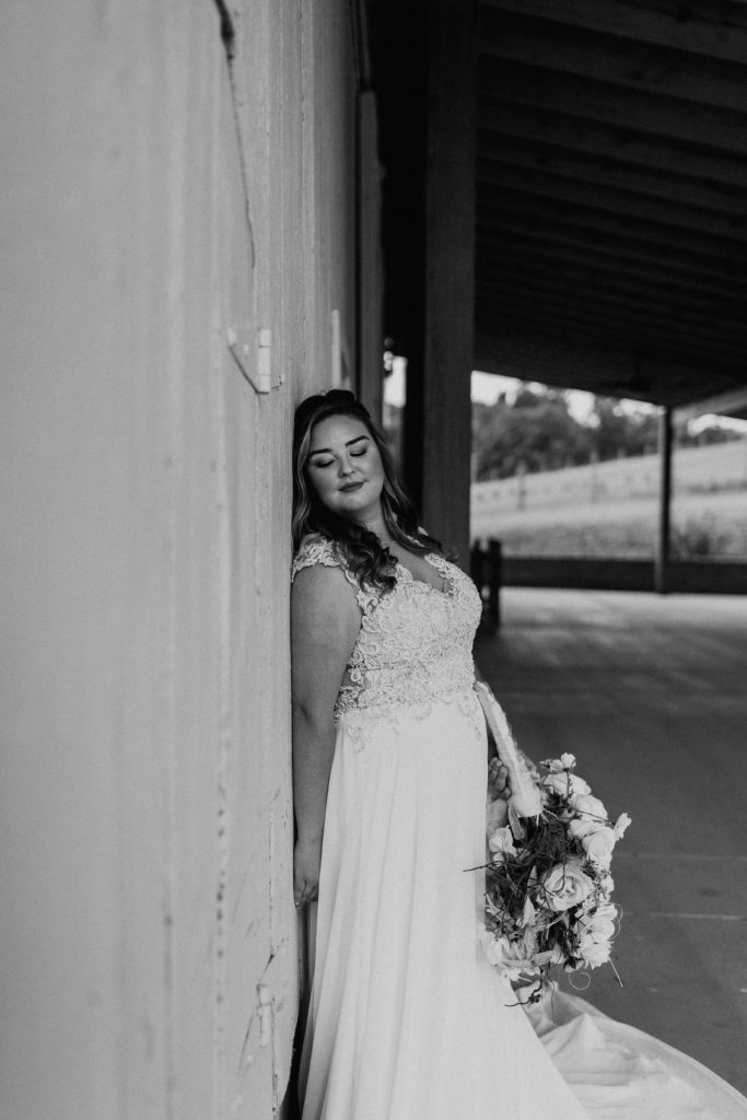 black and white photo of bride leaning against wall 