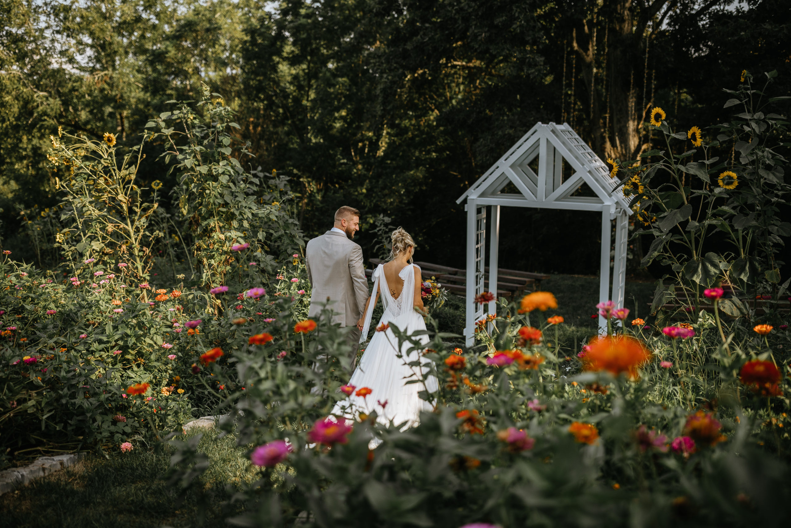 Bride and Groom walking through field of Zinnias at Greenwood Oaks Wedding and Event Venue
