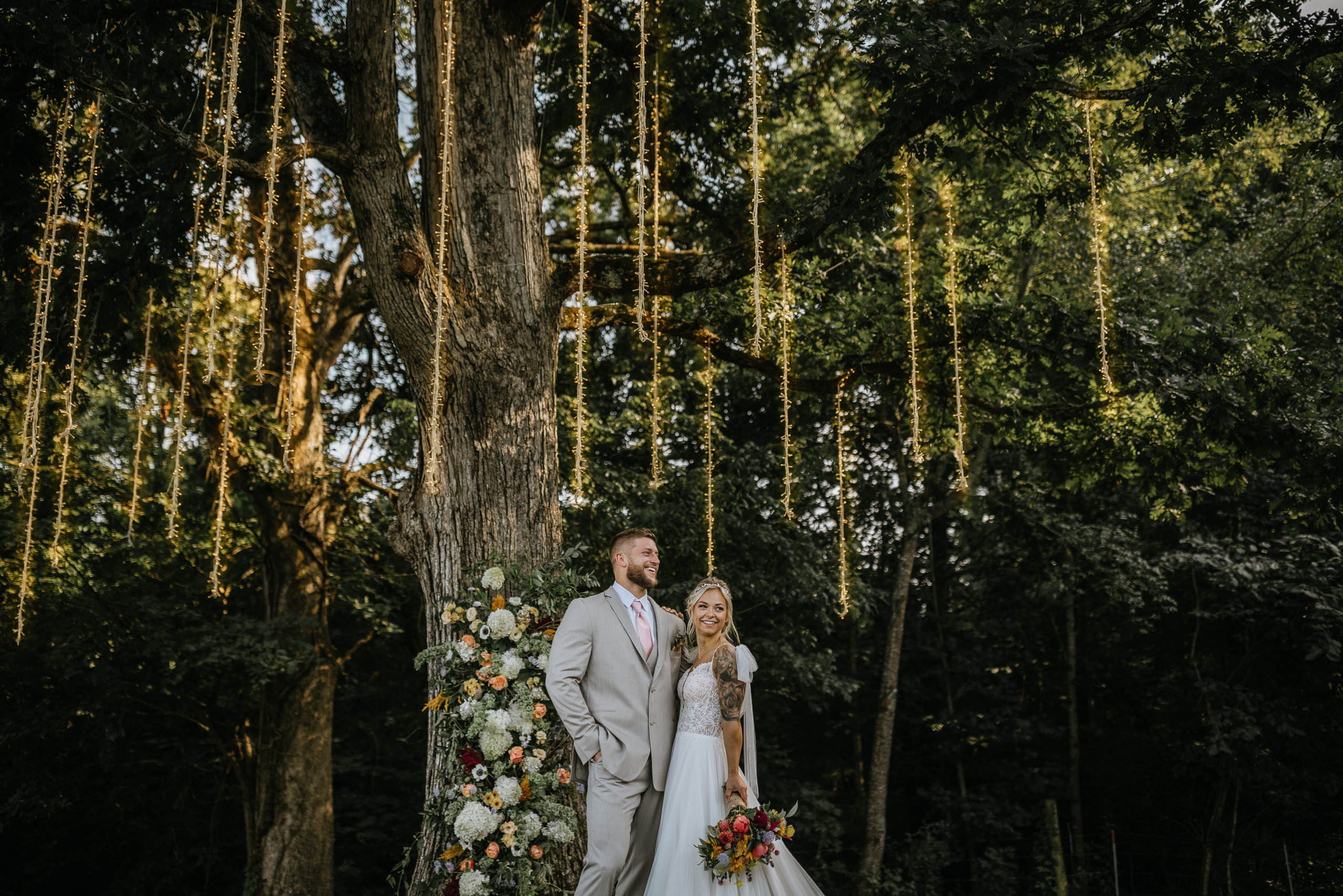 bride and groom standing under oak tree at greenwood oaks wedding venue in east tennessee