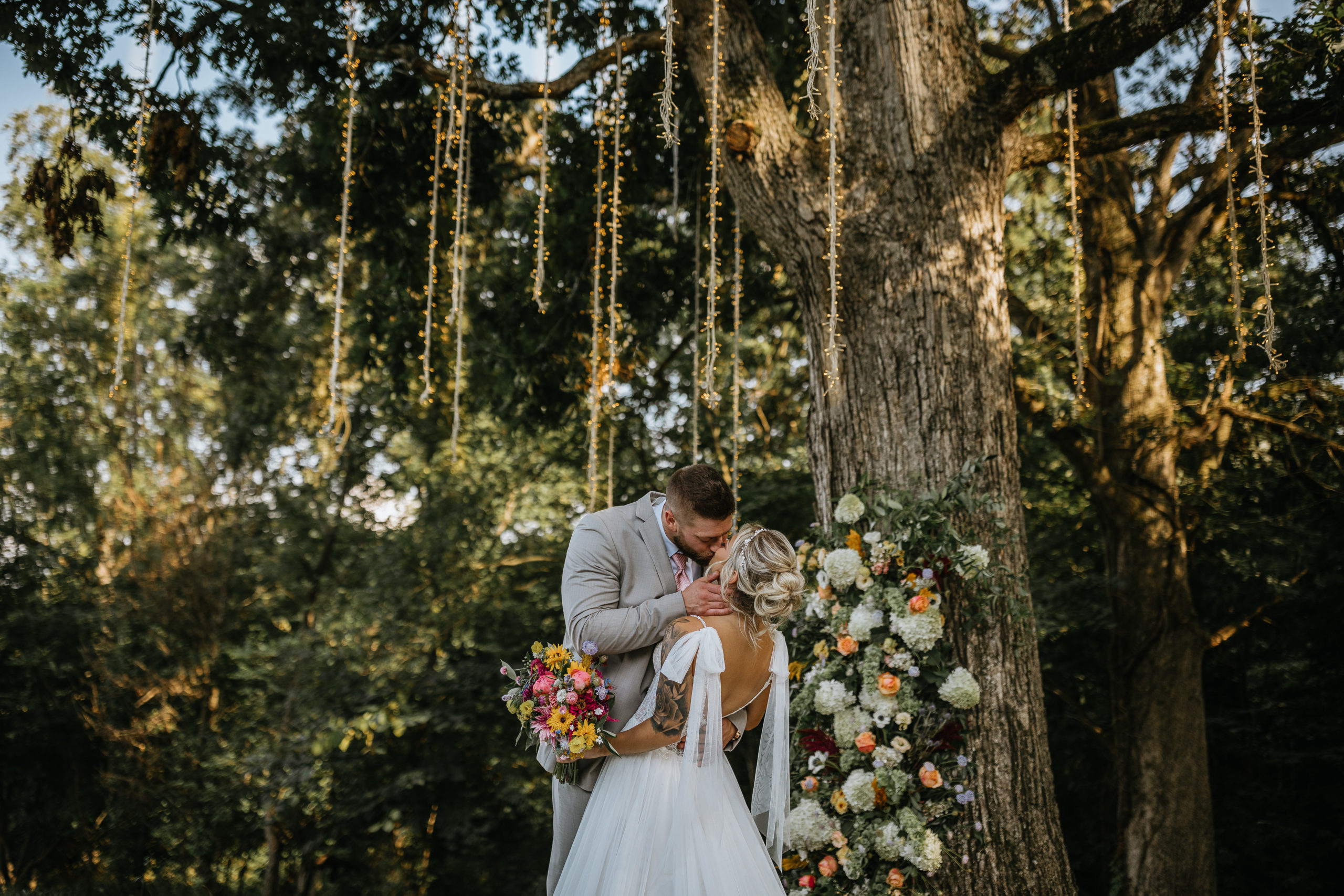 bride and groom kissing underneath an oak tree and string lights at greenwood oaks
