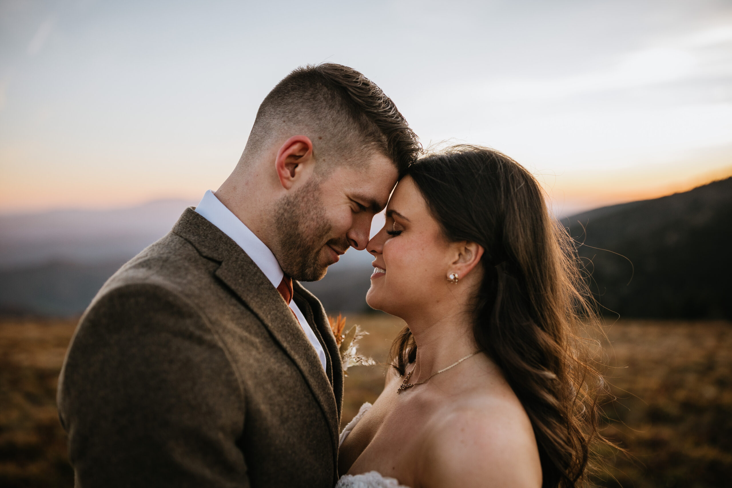 bride and groom standing with foreheads together on top of roan mountain in east tennessee