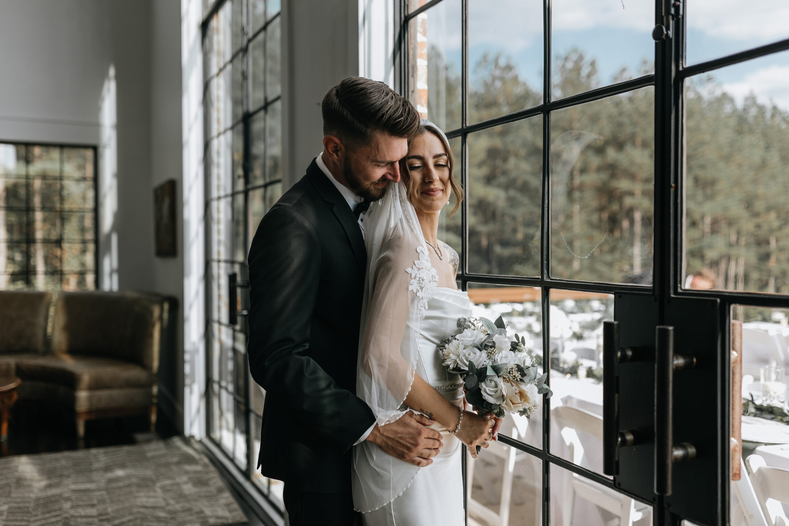 bride and groom stand and cuddle in front of window of the airbnb they were married in chattanooga tennessee